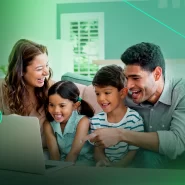 Família sorridente assistindo algo em um laptop