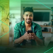 Homem sorridente usando smartphone em casa