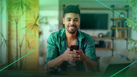 Homem sorridente usando smartphone em casa