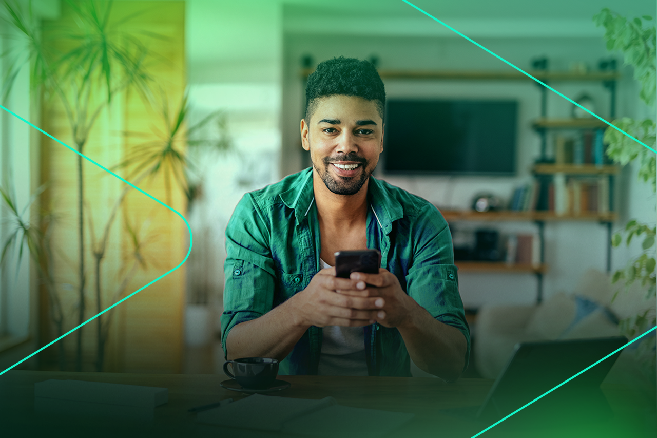 Homem sorridente usando smartphone em casa