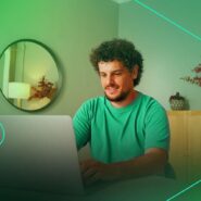 Homem sorrindo enquanto trabalha no laptop em casa.