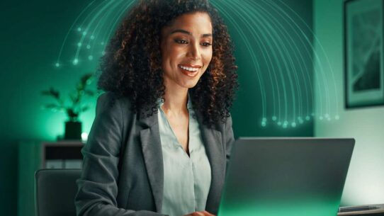 Mulher sorrindo usando laptop em ambiente moderno