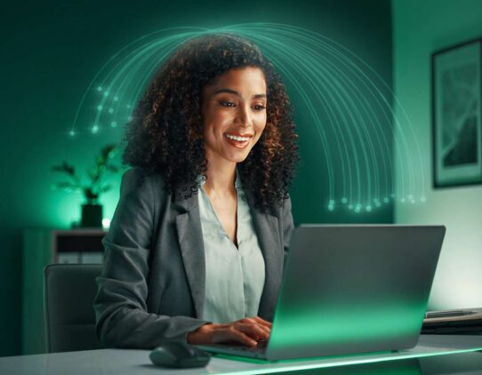 Mulher sorrindo usando laptop em ambiente moderno
