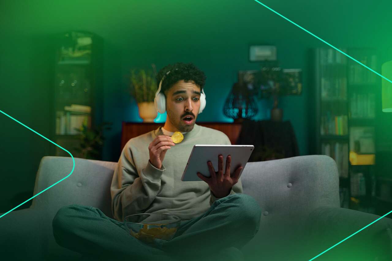 Homem assistindo vídeo com tablet e salgadinhos