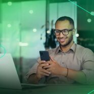 Homem sorridente usando smartphone no trabalho.