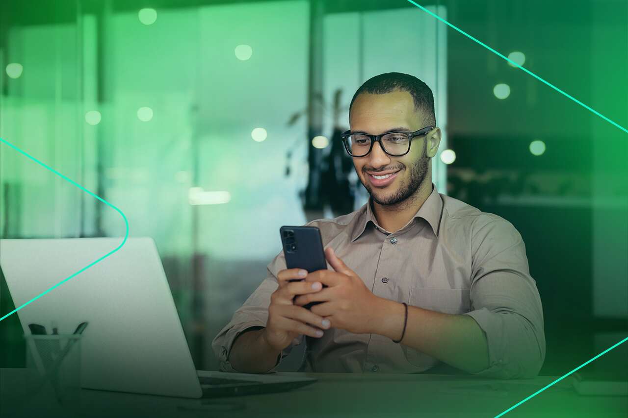 Homem sorridente usando smartphone no trabalho.