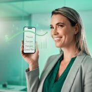 Mulher segurando smartphone com gráficos financeiros.