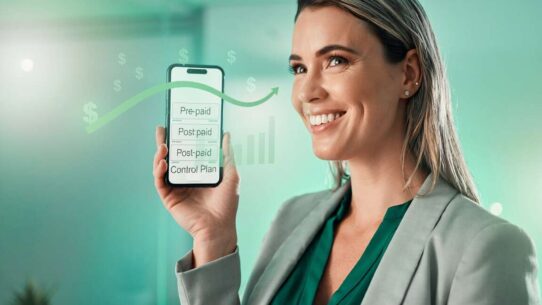 Mulher segurando smartphone com gráficos financeiros.