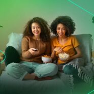 Mulheres assistindo TV com pipoca e refrigerante