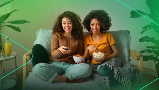 Mulheres assistindo TV com pipoca e refrigerante