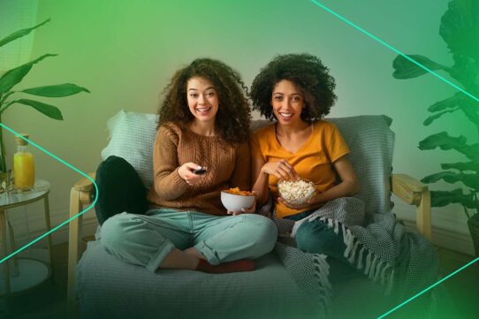 Mulheres assistindo TV com pipoca e refrigerante