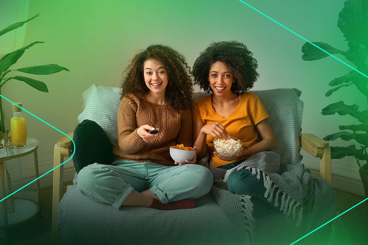 Mulheres assistindo TV com pipoca e refrigerante