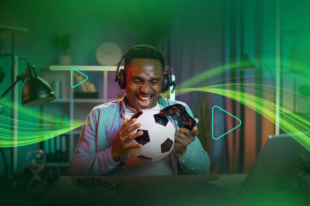 Homem sorridente jogando futebol em um videogame.