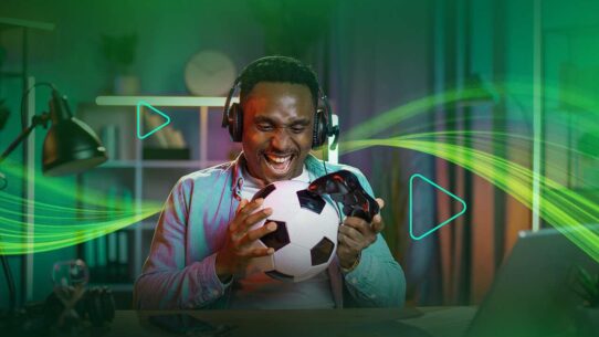 Homem sorridente jogando futebol em um videogame.