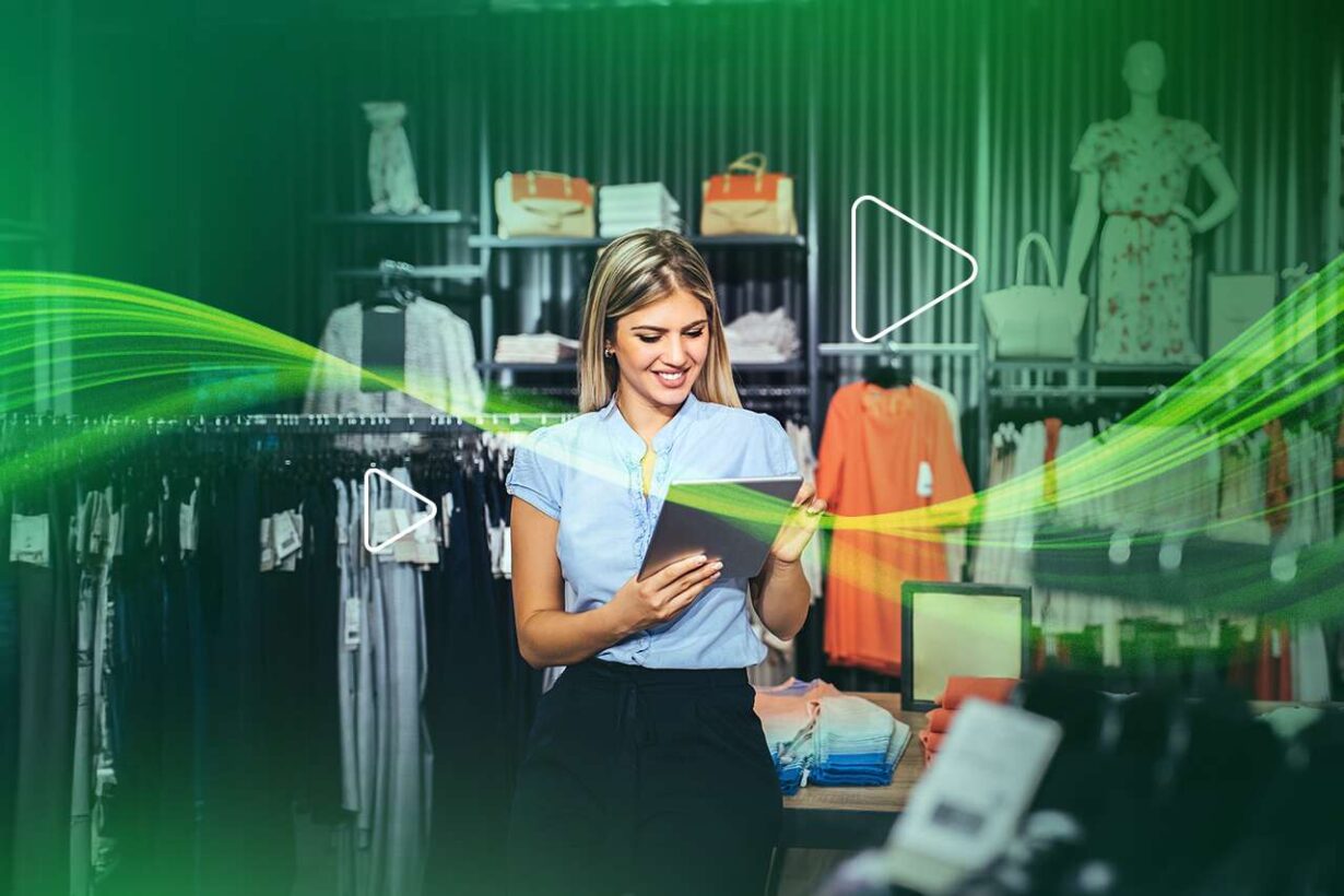 Mulher sorrindo em loja de roupas usando tablet