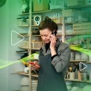Mulher em loja falando ao telefone e usando celular.