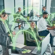 Colaboradores em escritório moderno com tecnologia conectada.