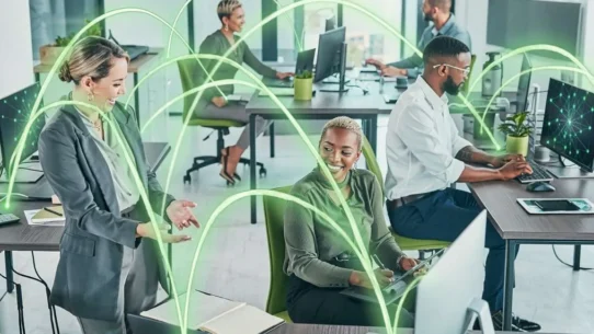 Colaboradores em escritório moderno com tecnologia conectada.