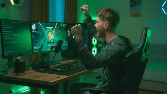 Jovem comemorando vitória em jogo de computador.