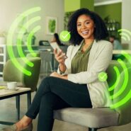 Mulher sorrindo usando smartphone em ambiente moderno.