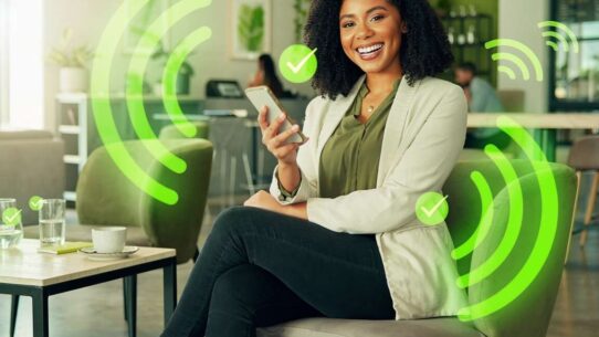 Mulher sorrindo usando smartphone em ambiente moderno.
