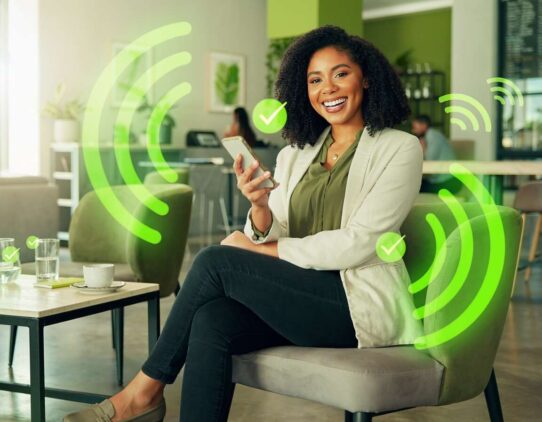 Mulher sorrindo usando smartphone em ambiente moderno.