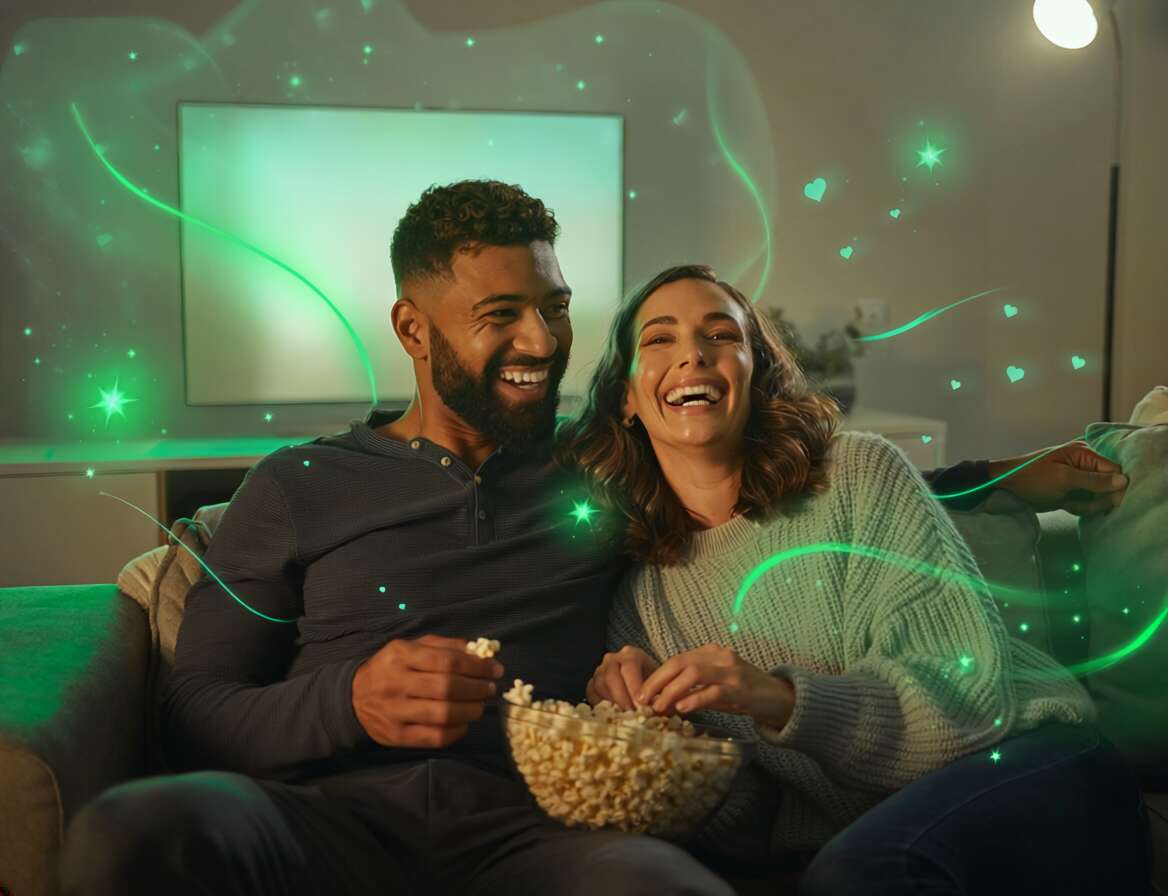 Casal sorrindo e assistindo filme com pipoca.