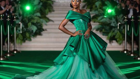 Modelo com vestido verde em evento glamouroso.