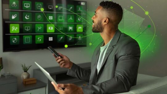 Homem controlando TV com tablet na mão.