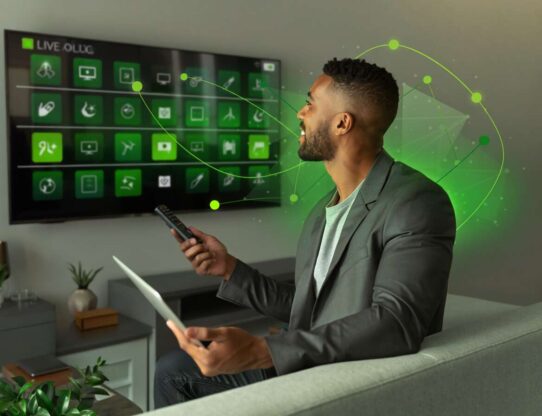 Homem controlando TV com tablet na mão.