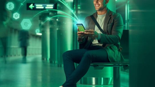 Homem usando smartphone em ambiente moderno e iluminado.