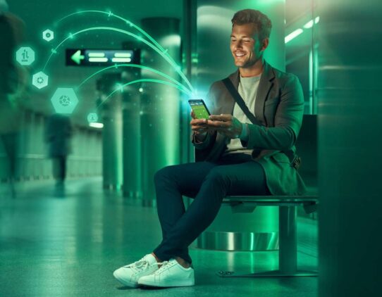 Homem usando smartphone em ambiente moderno e iluminado.