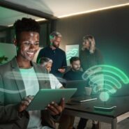 Homem sorrindo usando tablet em ambiente de trabalho moderno.