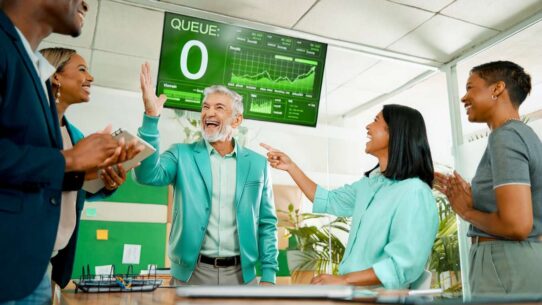Grupo de pessoas comemorando em ambiente de trabalho moderno.