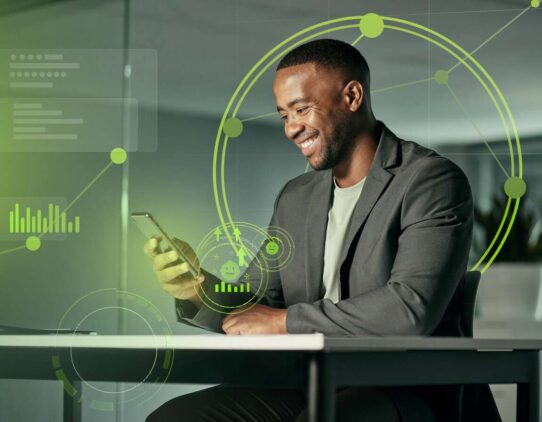 Homem sorridente usando celular em ambiente moderno.