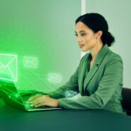 Mulher usando laptop com ícones de email em verde.